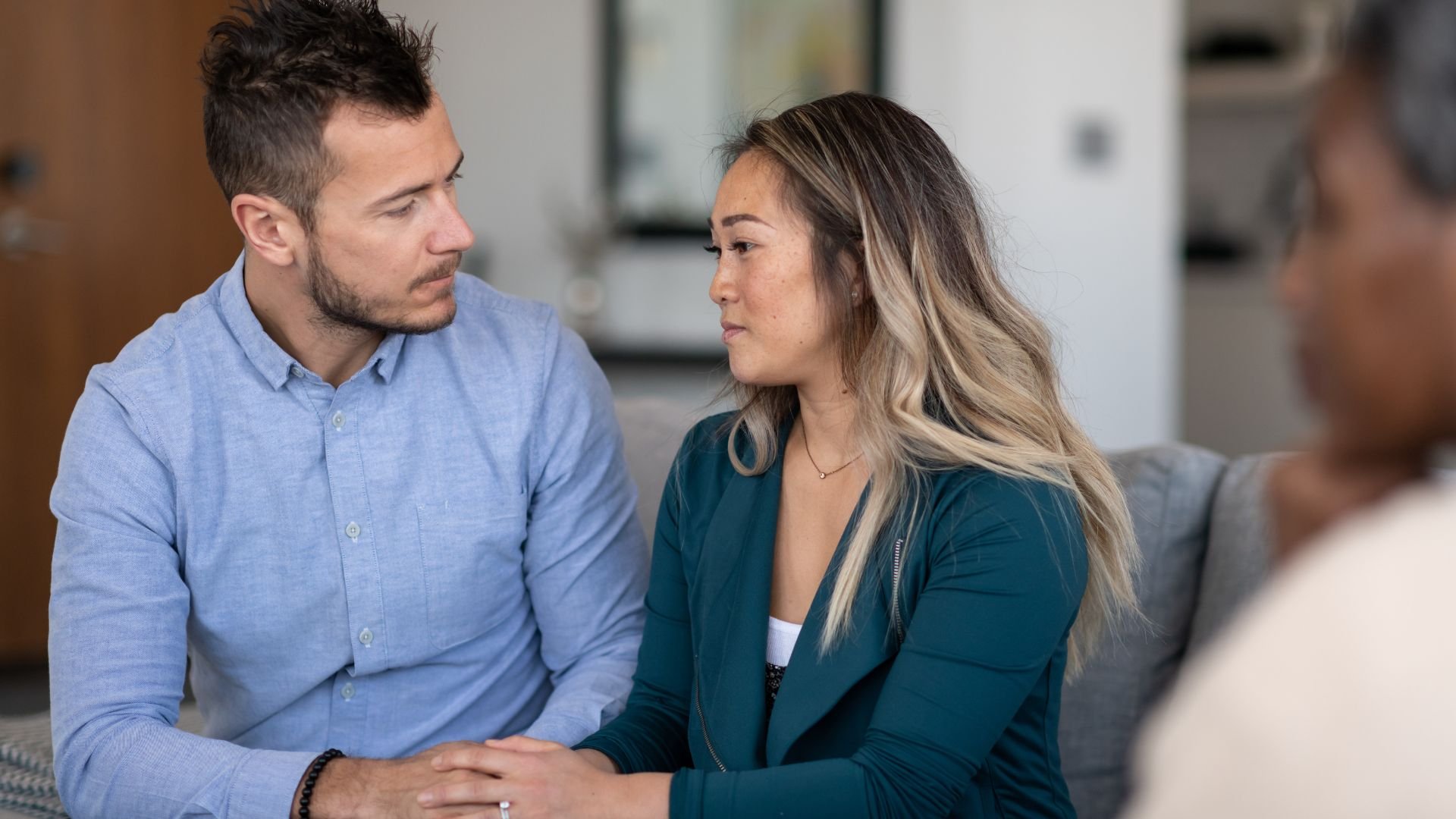 Two people in serious conversation sitting close together on a couch