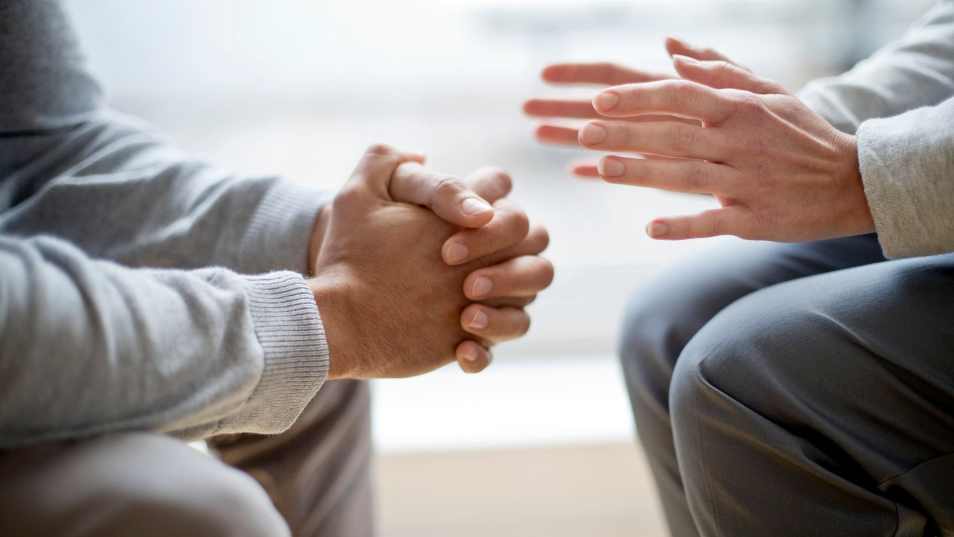 Two people holding hands in supportive, comforting counseling session