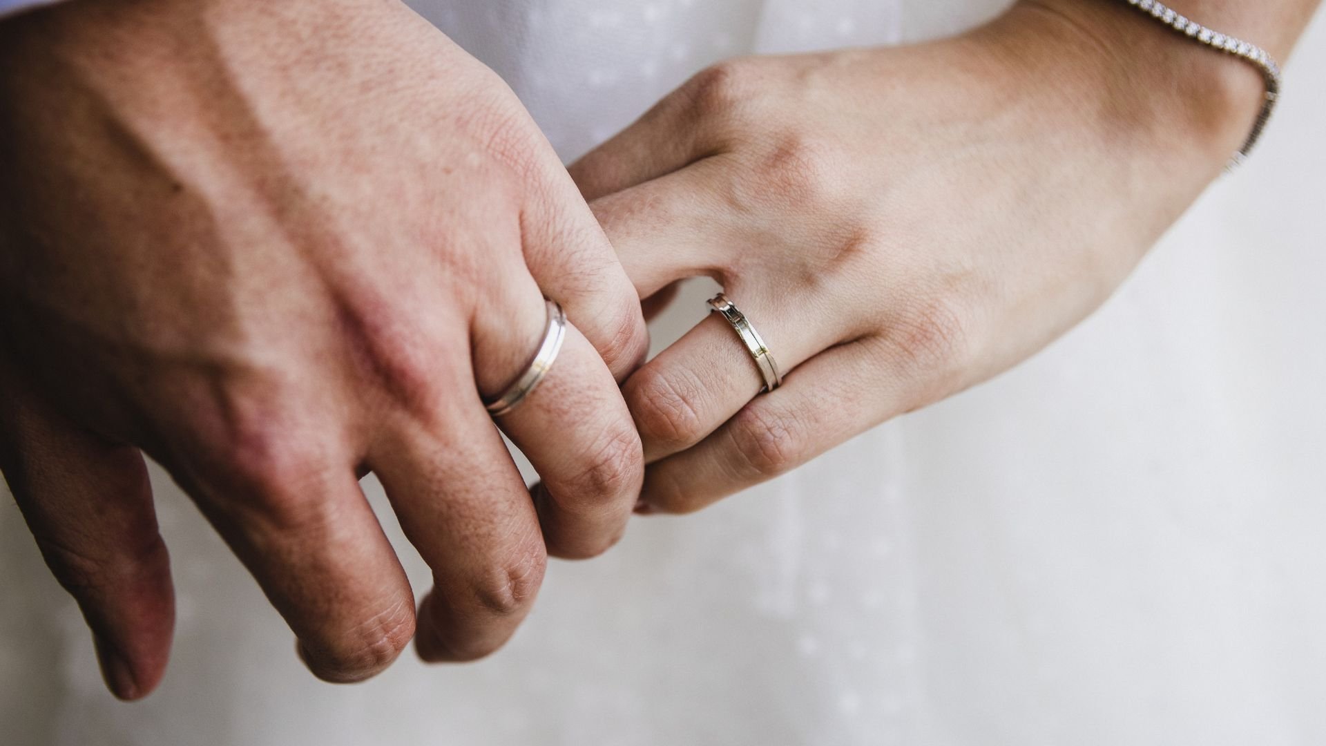 Hands with wedding rings intertwined, symbolizing love and commitment